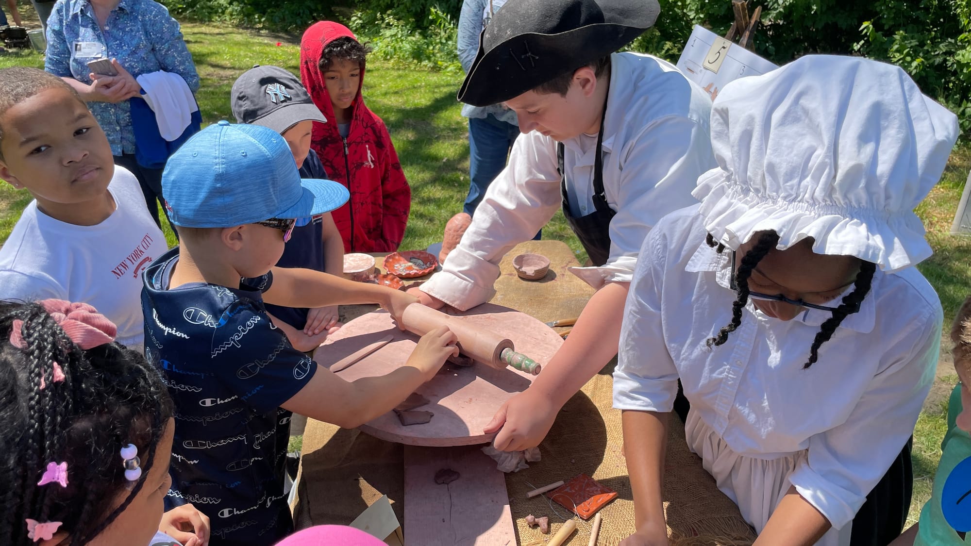 Fourth grade students flatten pottery materials.