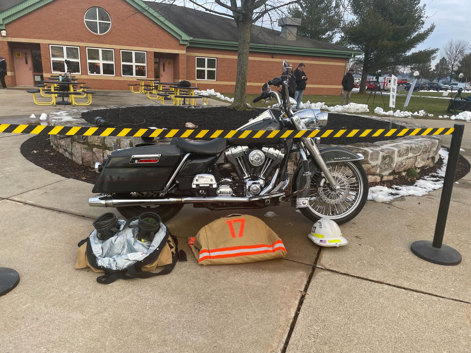 Mourners in dress uniforms outside passed by Paris' prized Harley-Davidson and a display of his fire gear.