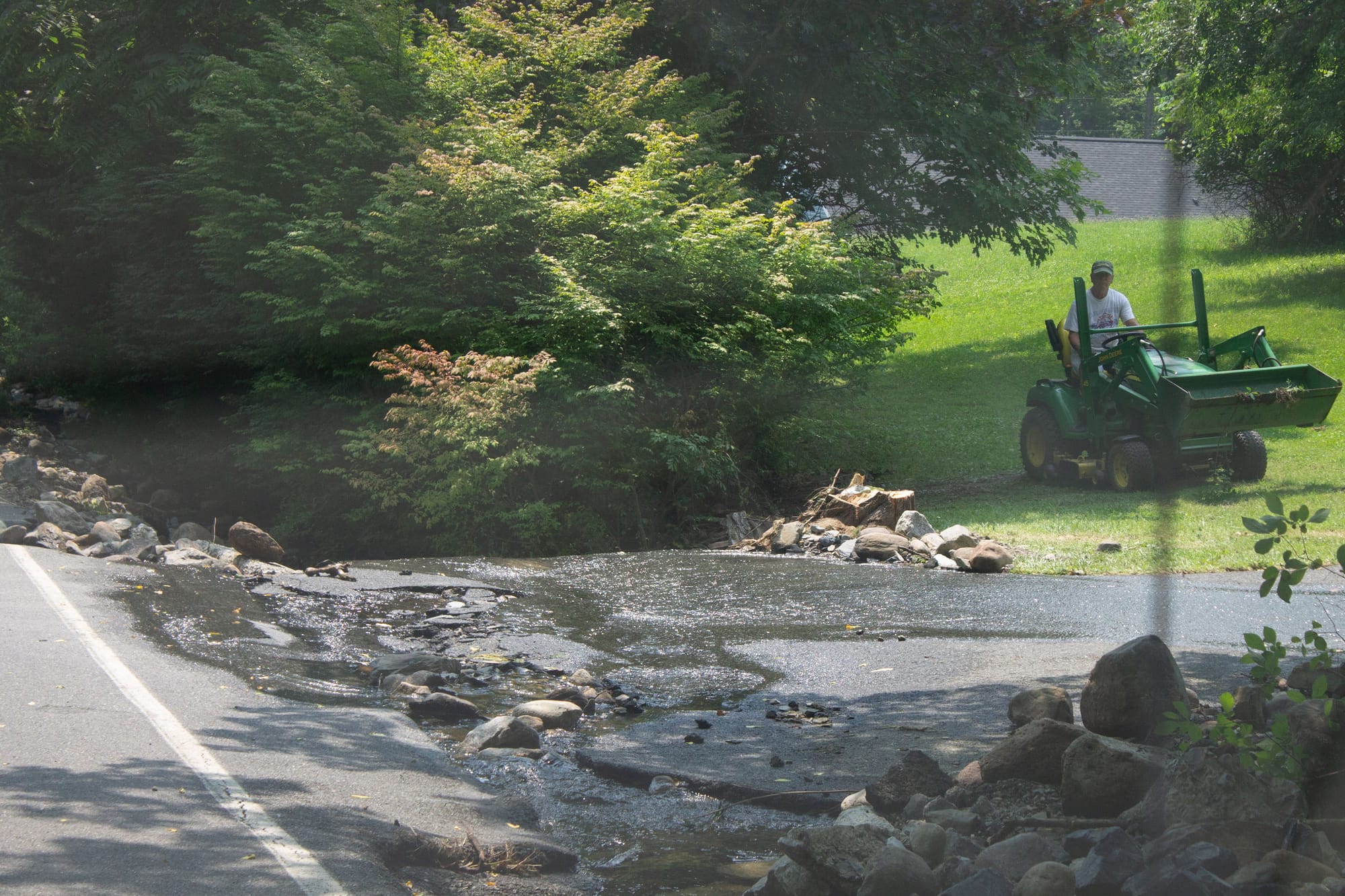 A man mows his lawn, avoiding the flooded area.