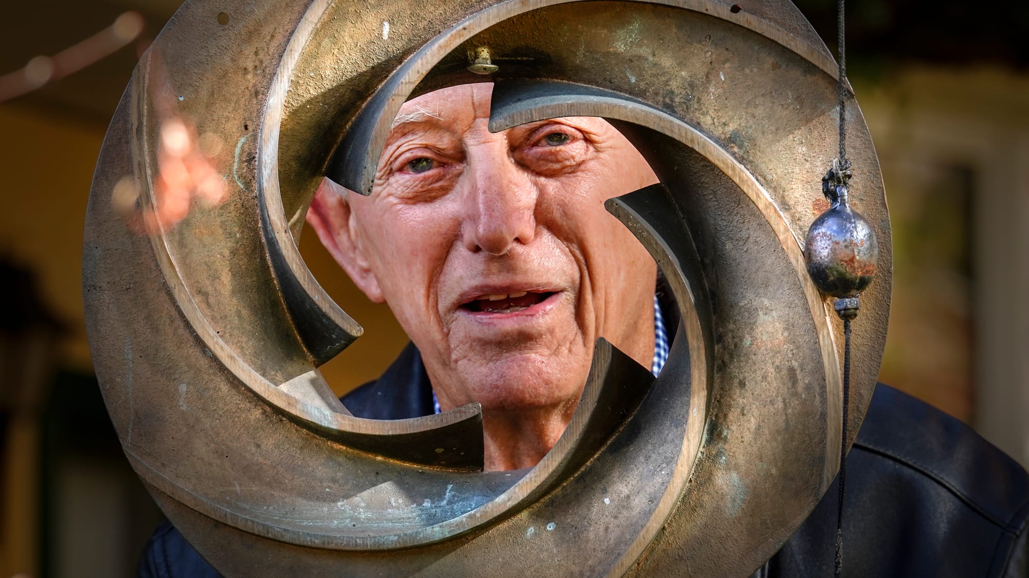 Fred Buse, a former marine engineer, peers through an impeller that was part of a working pump and is now a wind chime on his