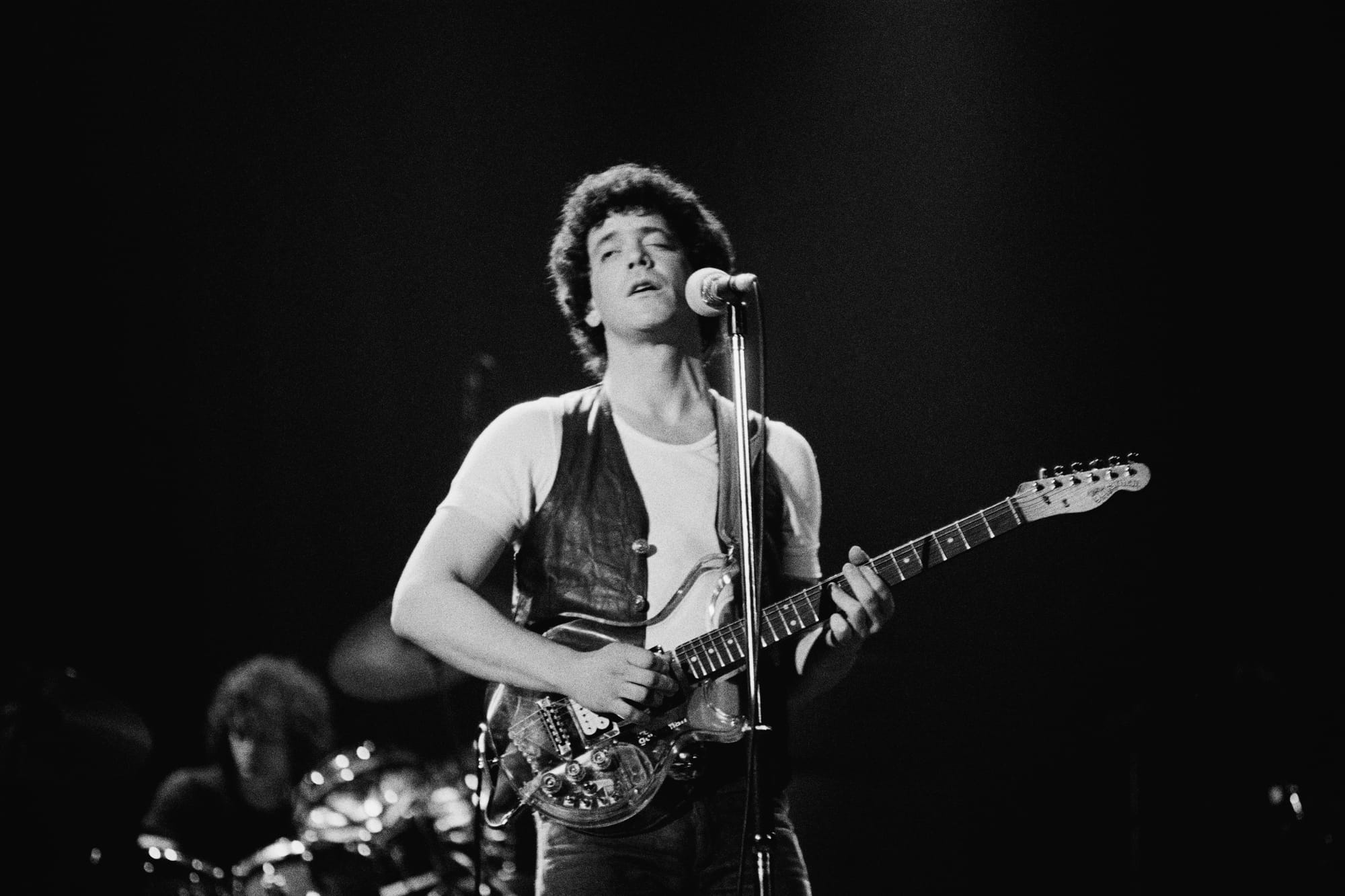 American rock singer-songwriter Lou Reed performs at the Hammersmith Odeon in London in 1975. He is playing a transparent, pl
