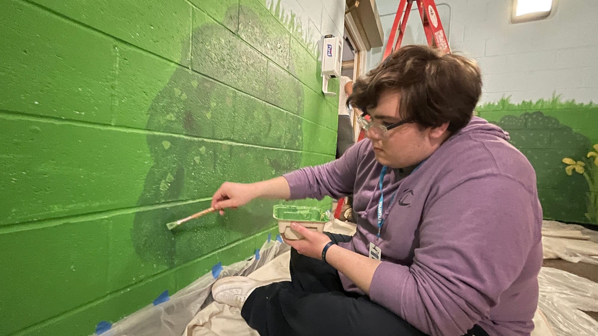 Liam O'Donnell, a junior at Freedom High School, touches up a bush with some bright green accents.