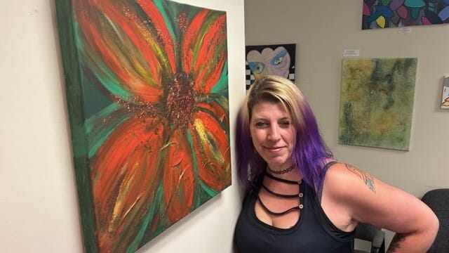 Angela Lender with her work on display at the Artists in Recovery exhibit.