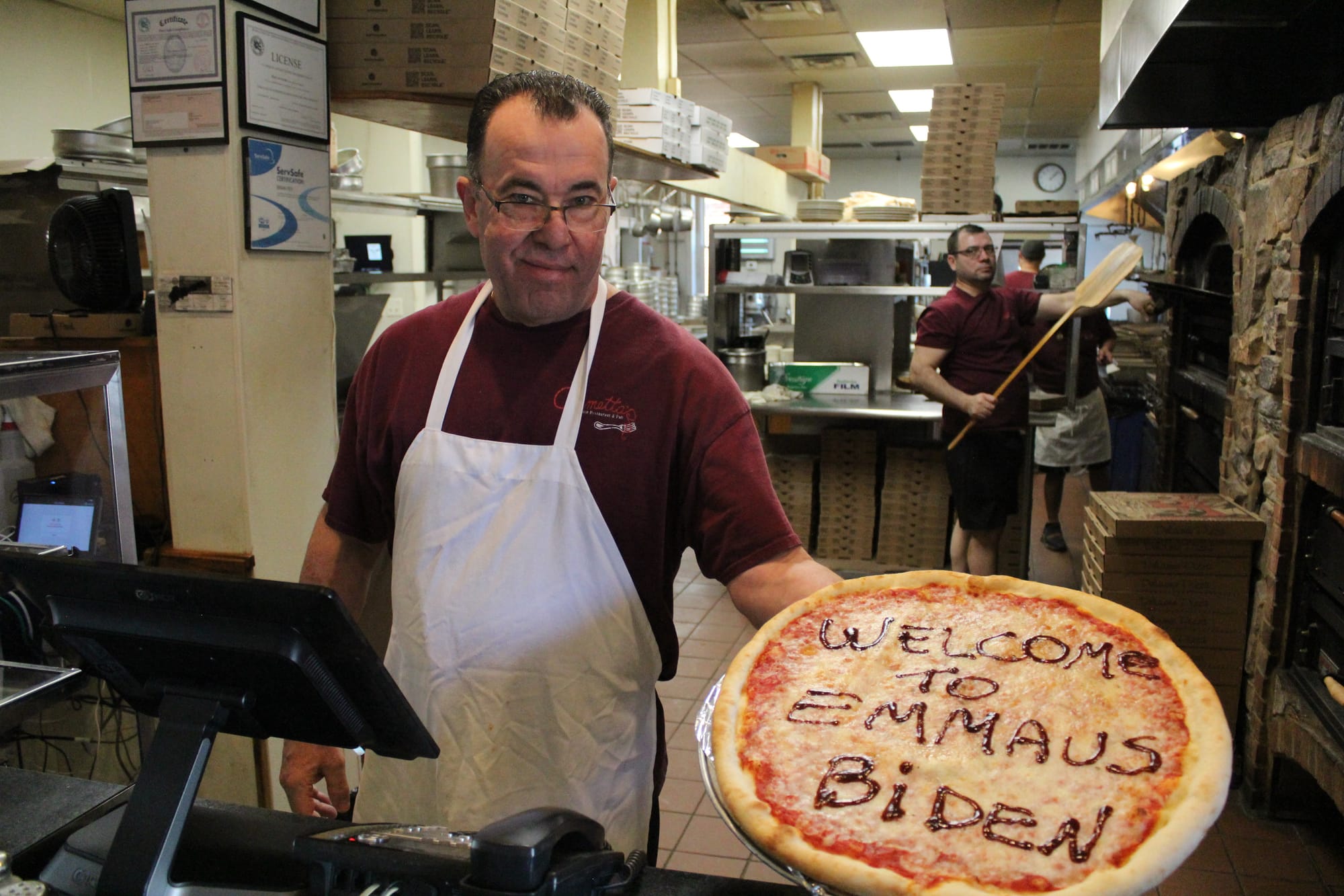 At Armetta's Italian Restaurant and Pub, Tony Ingrassia holds a pizza declaring "Welcome to Emmaus Biden" prior to President 