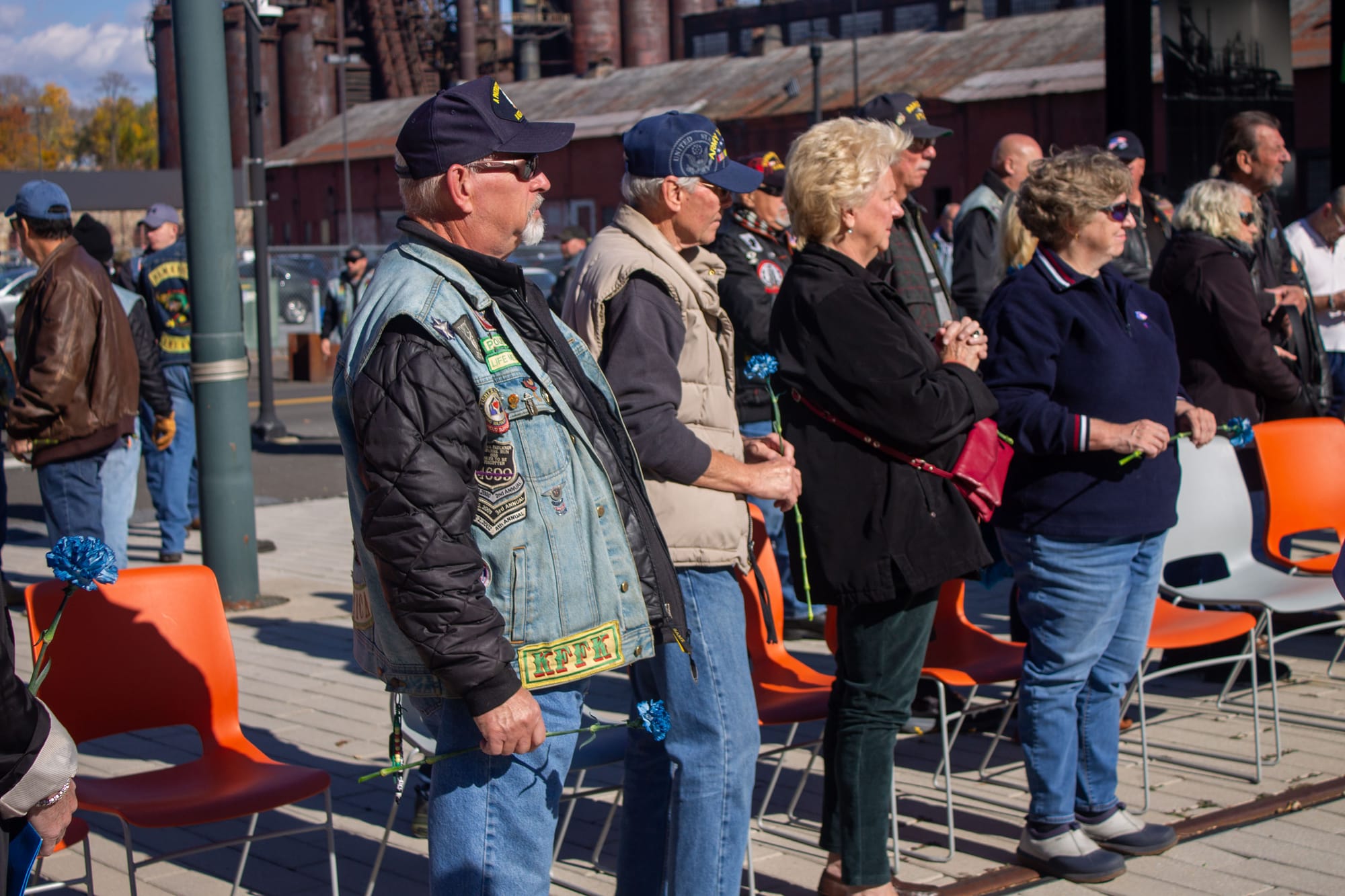 Veterans and family members, holding red, white, and blue roses.
