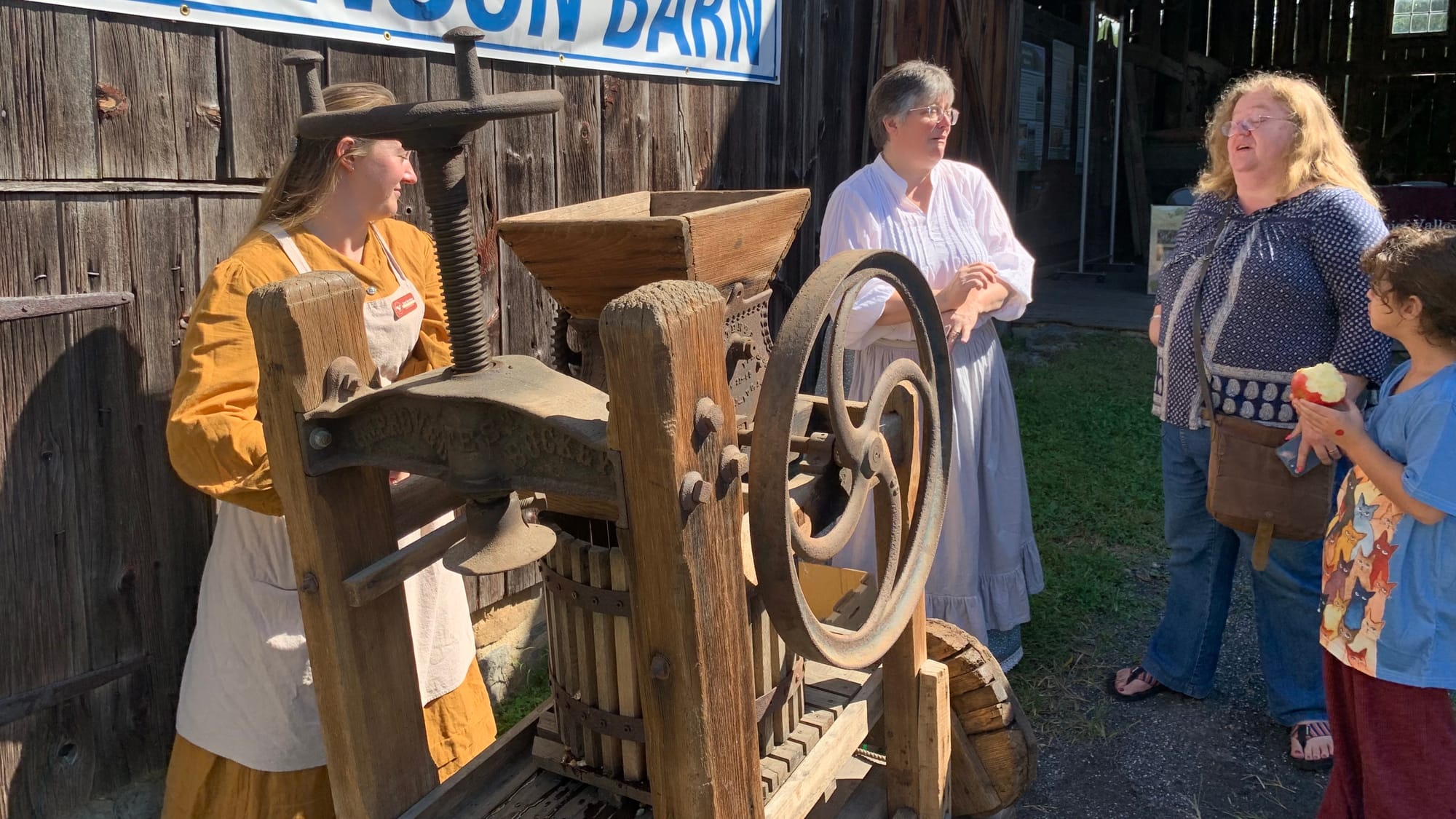 Women in period costumes make apple cider