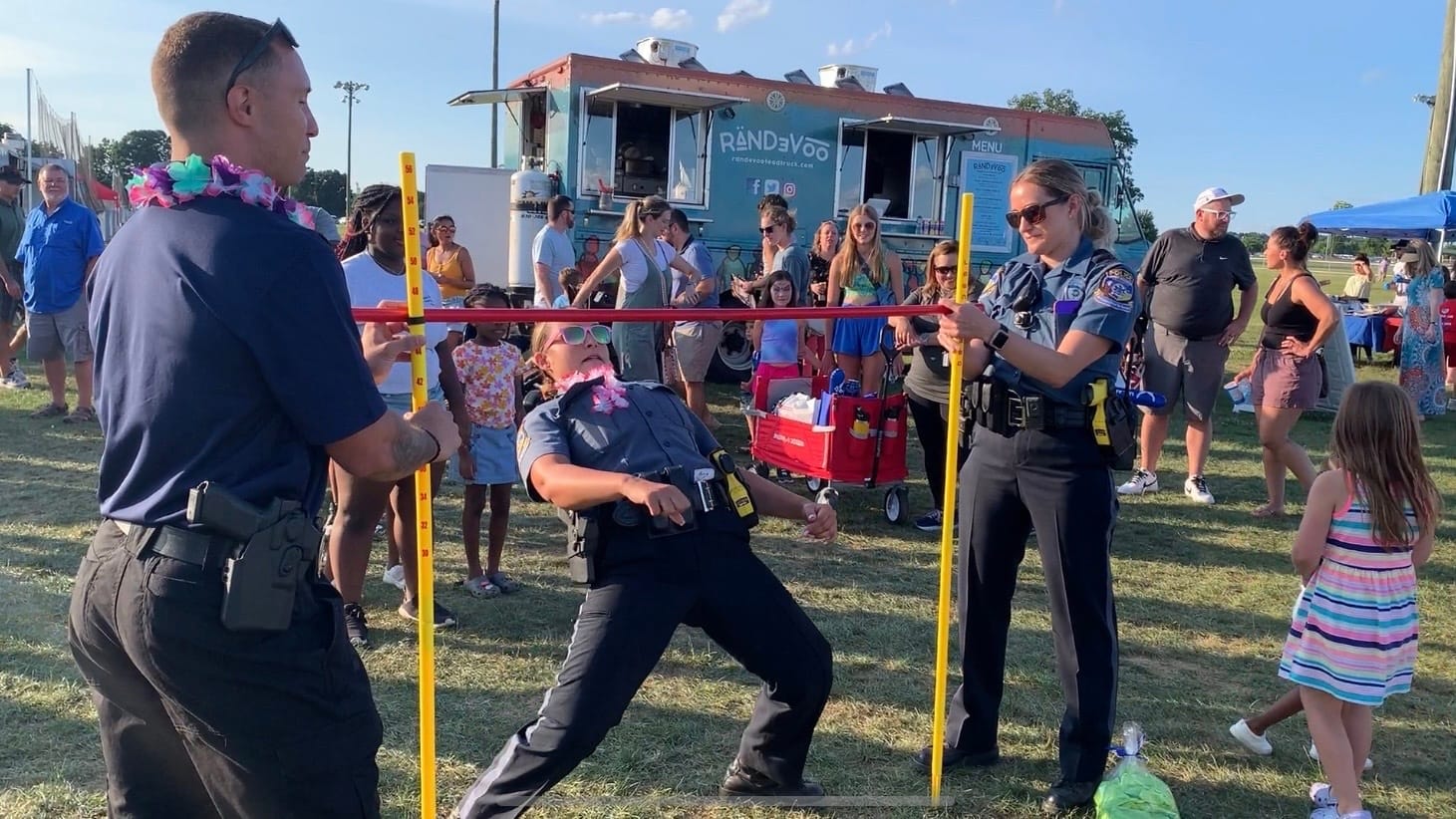 Officers and community members participate in a limbo competition at Upper Macungie's National Night Out event.