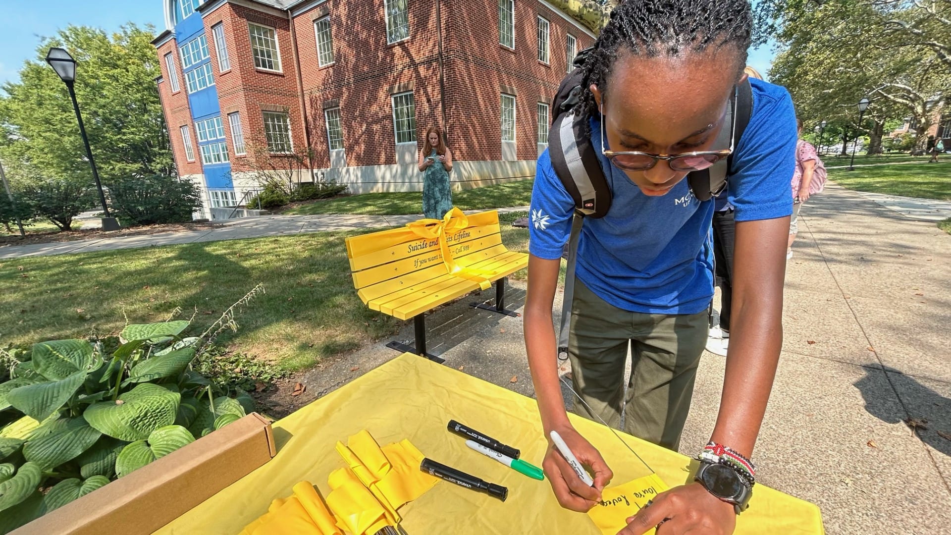 Moravian University student Neema Mburu signs flag in honor of suicide prevention.