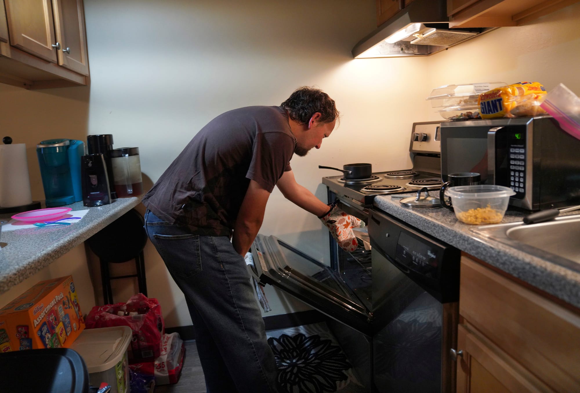 Andrew Hackney cooks dinner for his 1-year-old daughter during a supervised visit at his and his wife's apartment in Oakdale,