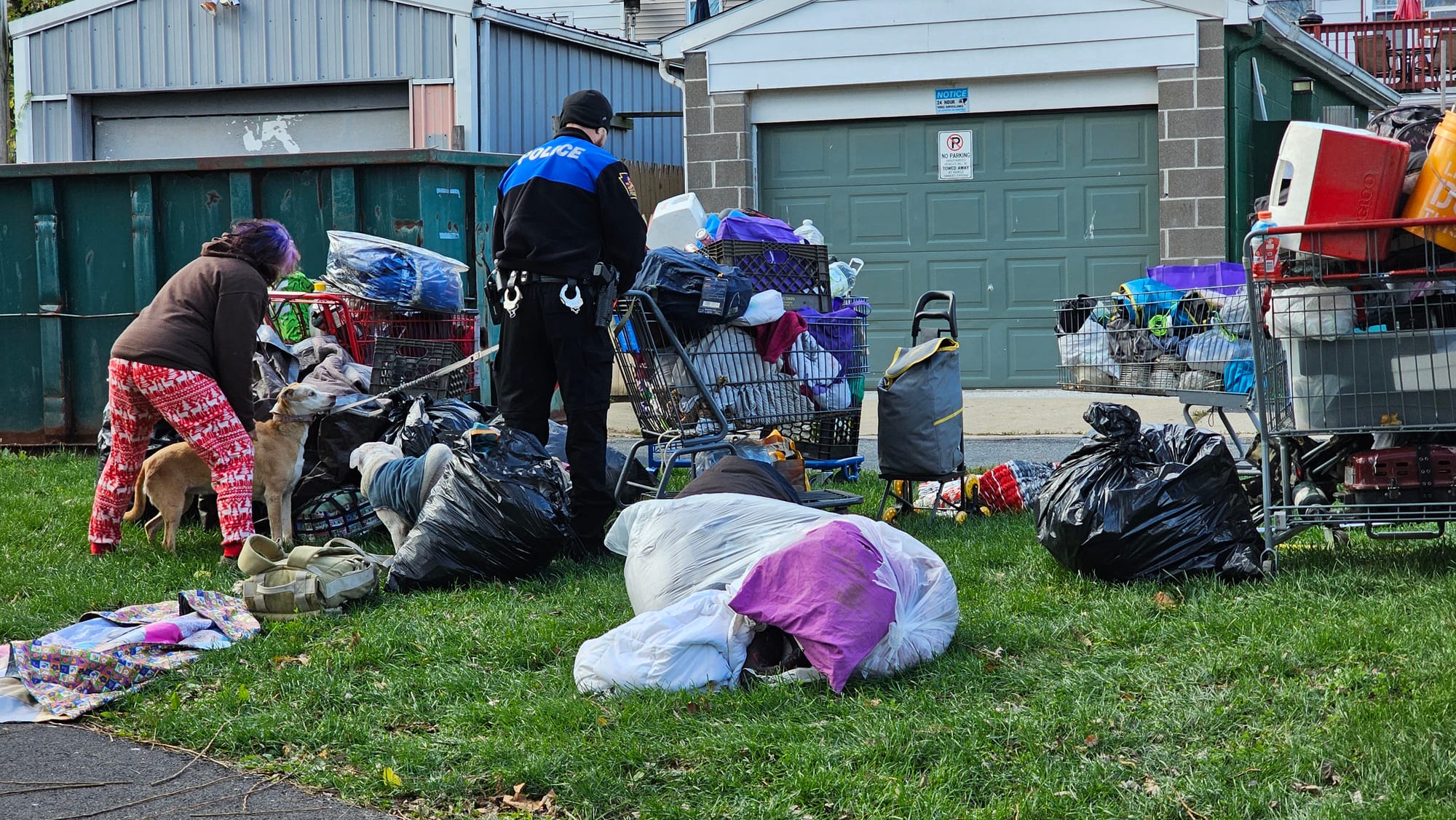 An Allentown police officer helps a resident with her dogs as crews work to clear the Jordan Creek Greenway encampment Monday