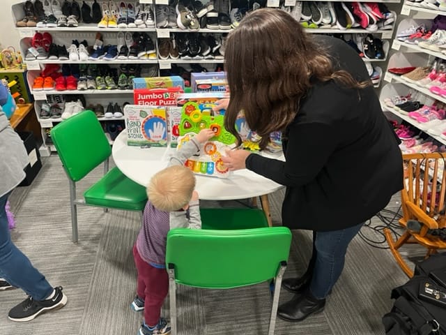The Kindness Project founder Jenae Holtzhafer helps a child pick out toys at the non-profit.