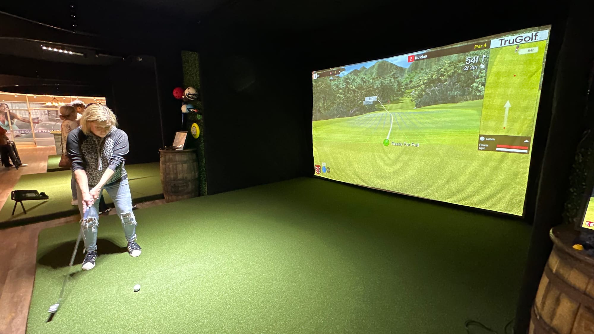 A visitor perfects her shot while playing simulator golf at Twisted Tees.