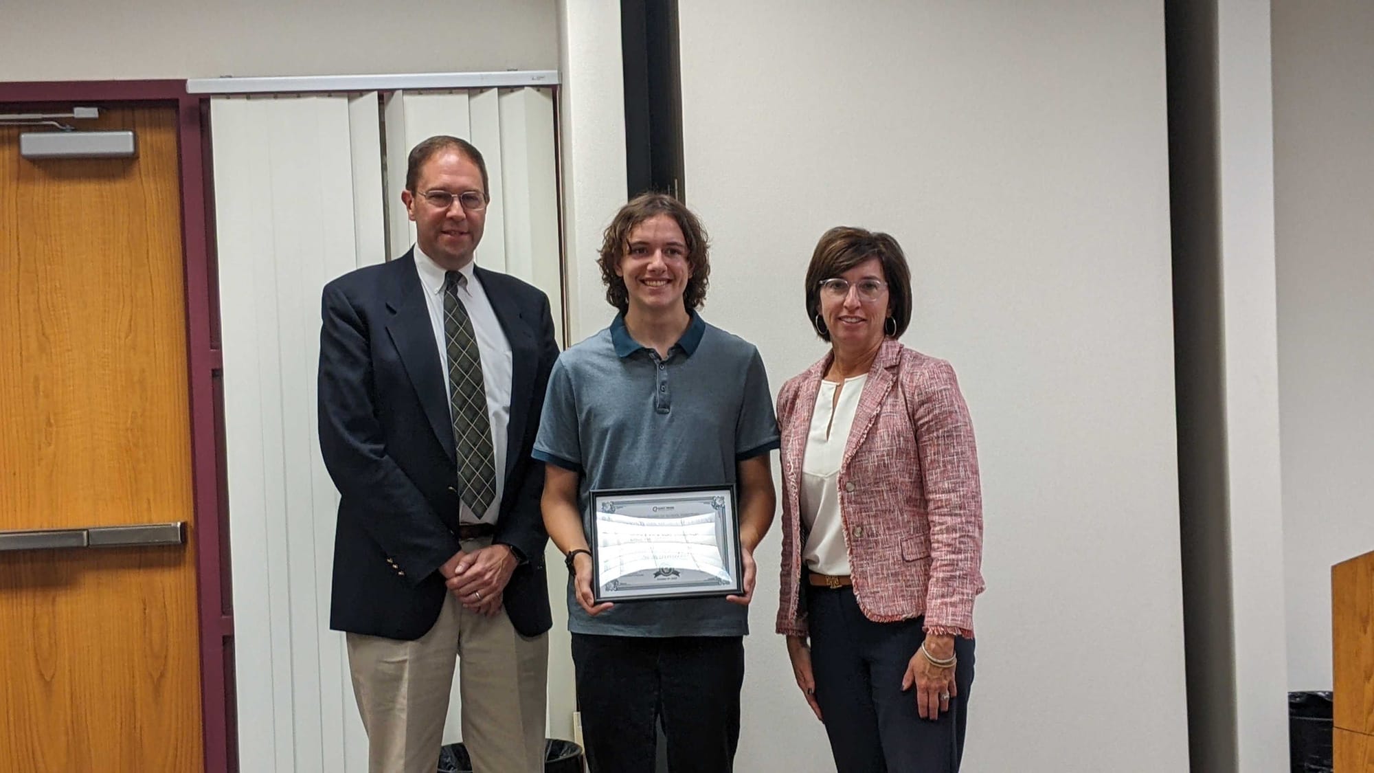 National Merit Scholarship semifinalist Benjamin Wiese with president of the board Joshua Levinson and superintendent Kristen