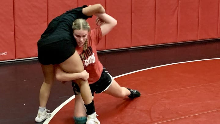 Girls practice wrestling moves at Easton Area High School. Ellia Sales is wearing a red shirt and Olivia Capra is wearing bla