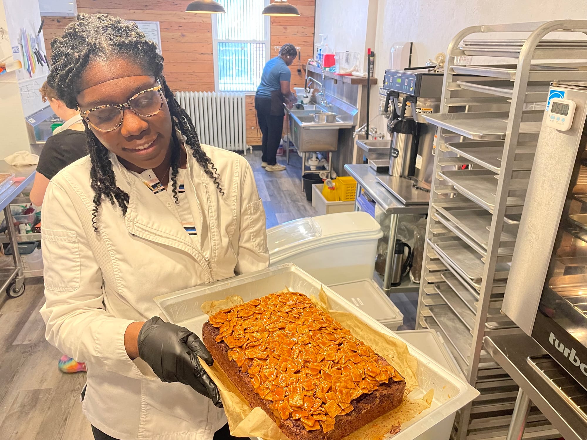Mia & Maddie's Bakery owner Eileen Newman removes a chocolate Cinnamon Toast Crunch brownie from the oven in her shop at 34 N