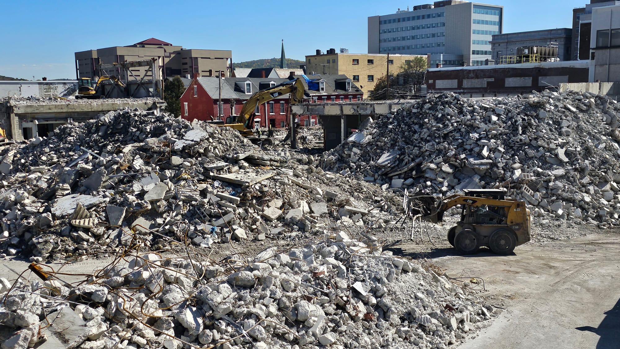 A bulldozer carries twisted metal through huge piles of rubble Tuesday, Oct. 24, at the site of the former Morning Call build