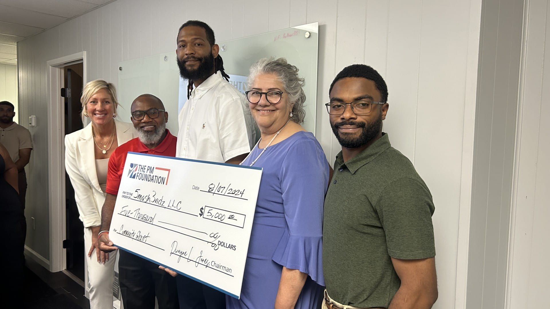 Travis Bonney (middle), founder of Serious Clamps Basketball Camp and 5mash 3ndz LLC., receives a check from the Preventative