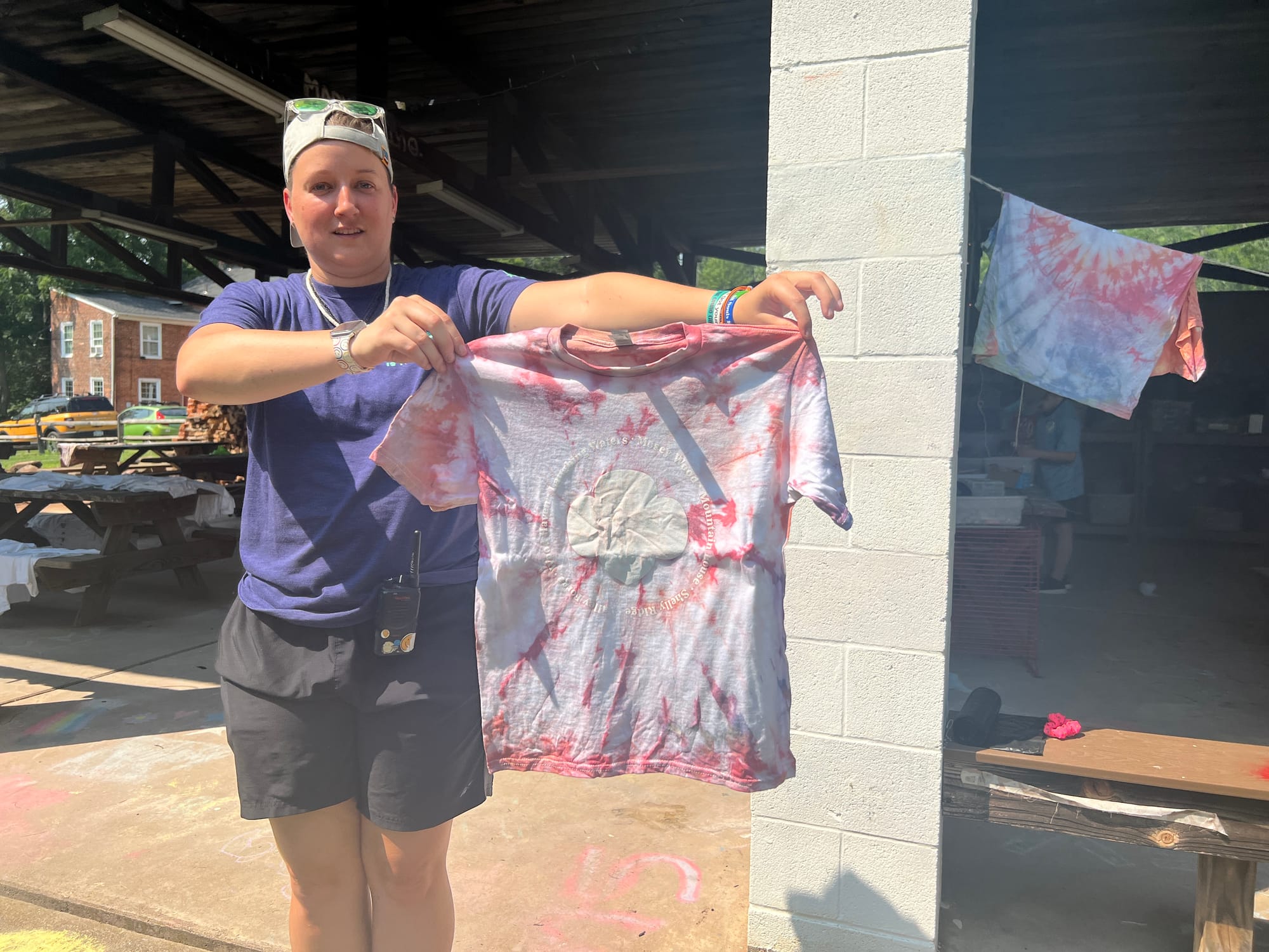 Camp Director Smilez demonstrates the GSEP shirts that get tie-dyed, with the names of all the camps in white ink around the 
