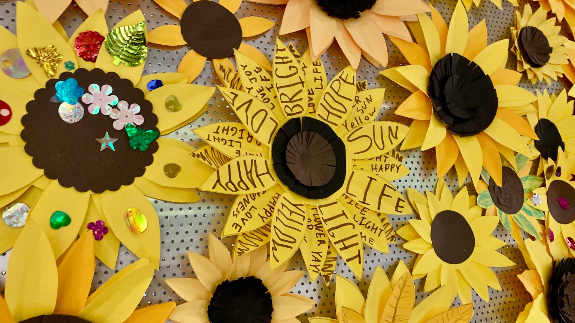 Some paper sunflowers at the entrance of 'Restoring Petals' had positive messages or decorations.