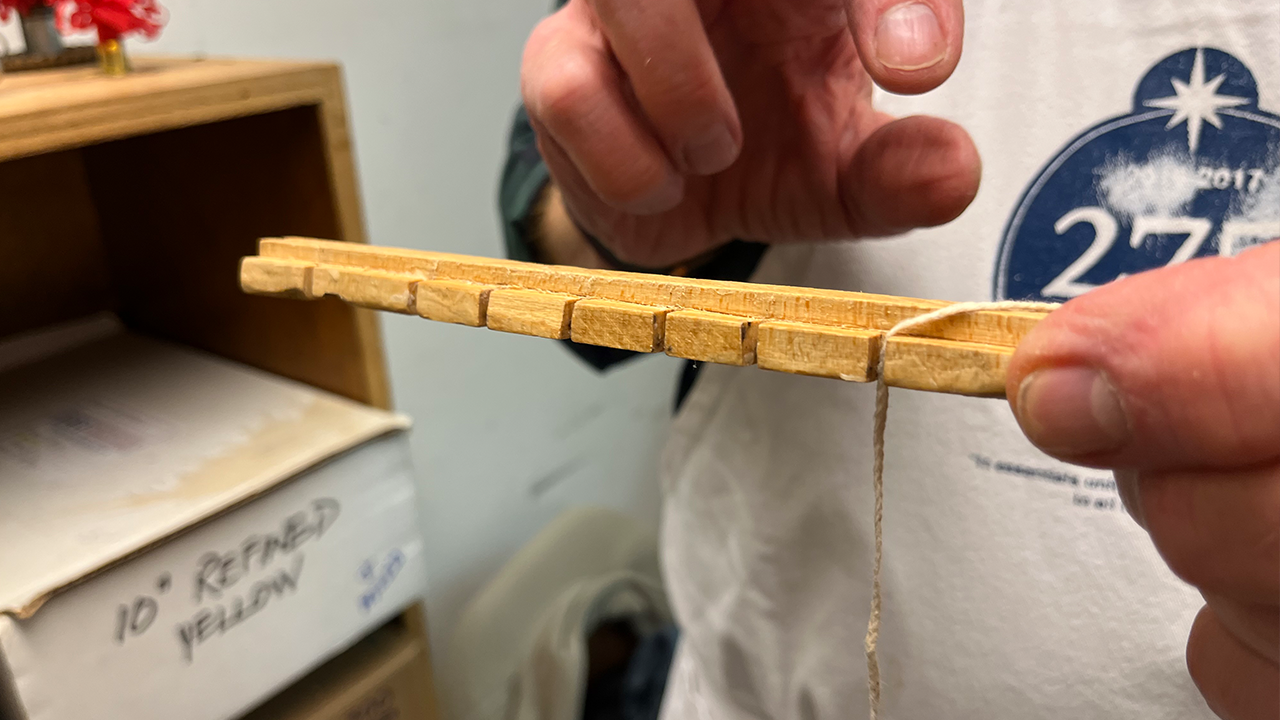 After they're waxed, volunteers lace the wicks through a holder that will be placed in the top of a mold.