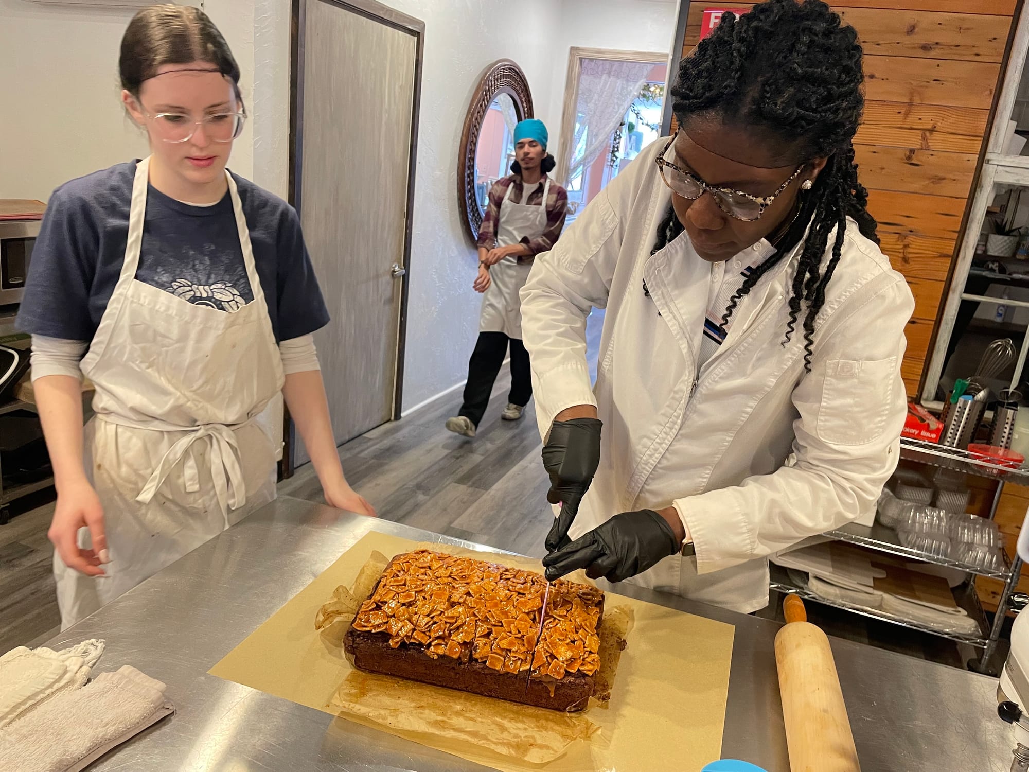 Eileen Newman cuts the brownie as baker Kendra Long looks on at Mia & Maddie's Bakery in Easton.
