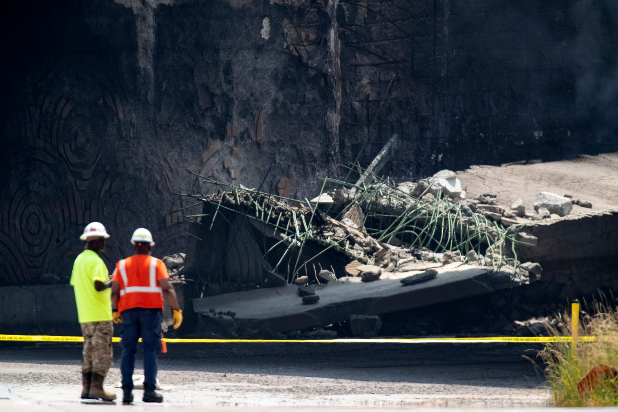 Officials work at the scene following the collapse of an elevated section of Interstate 95 after a tanker truck caught fire, 