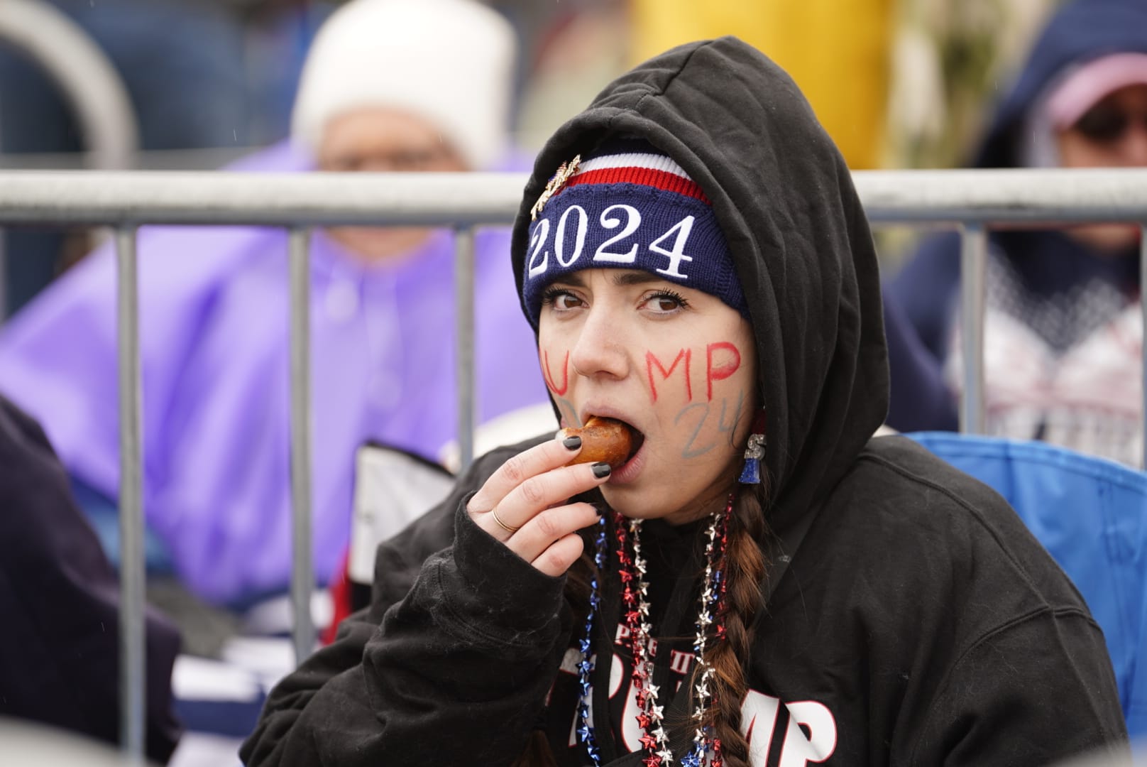 A Trump supporter snacks to keep warm as she waits for former President Donald Trump's visit to the Valley on Saturday.