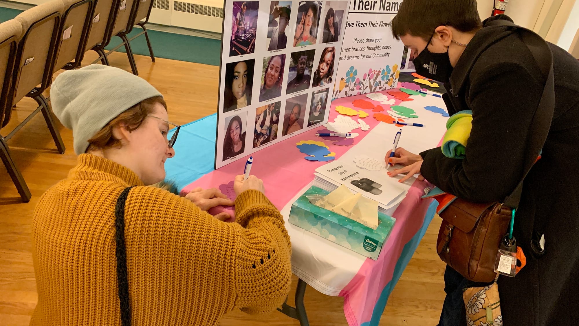 Community members write on paper flowers at the Transgender Day of Remembrance vigil.