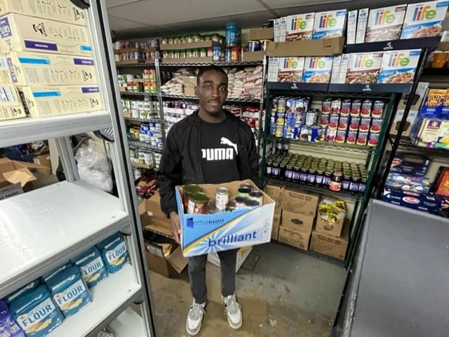Building 21 High School senior Jude-Philippe Belony helps to organize donations at Sixth Street Shelter in Allentown.