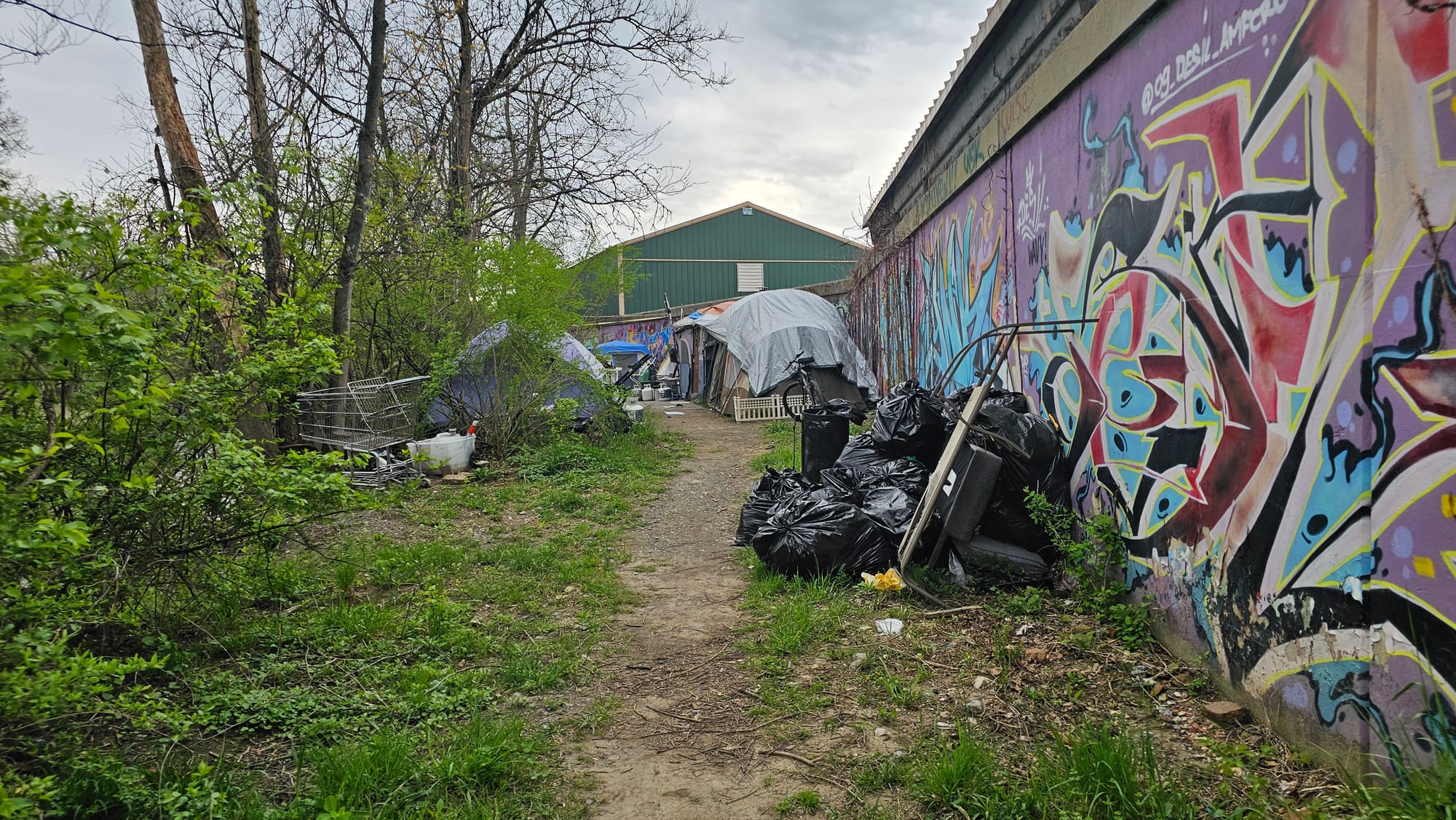 Tents and debris line a path along the Little Lehigh Creek and a retaining wall at Fountain Park. The small homeless camp is 