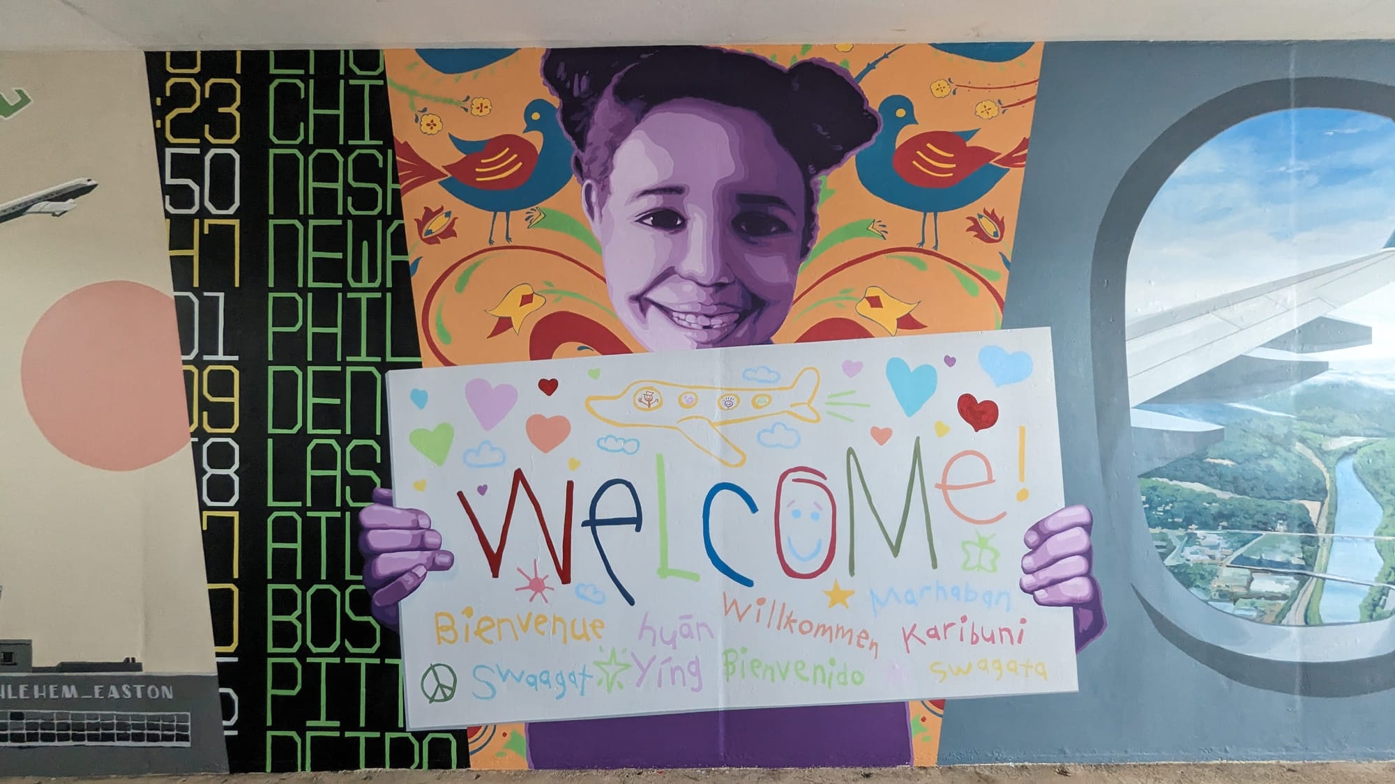 The centerpiece of a new mural at Lehigh Valley International Airport is a child holding a sign welcoming passengers to the V