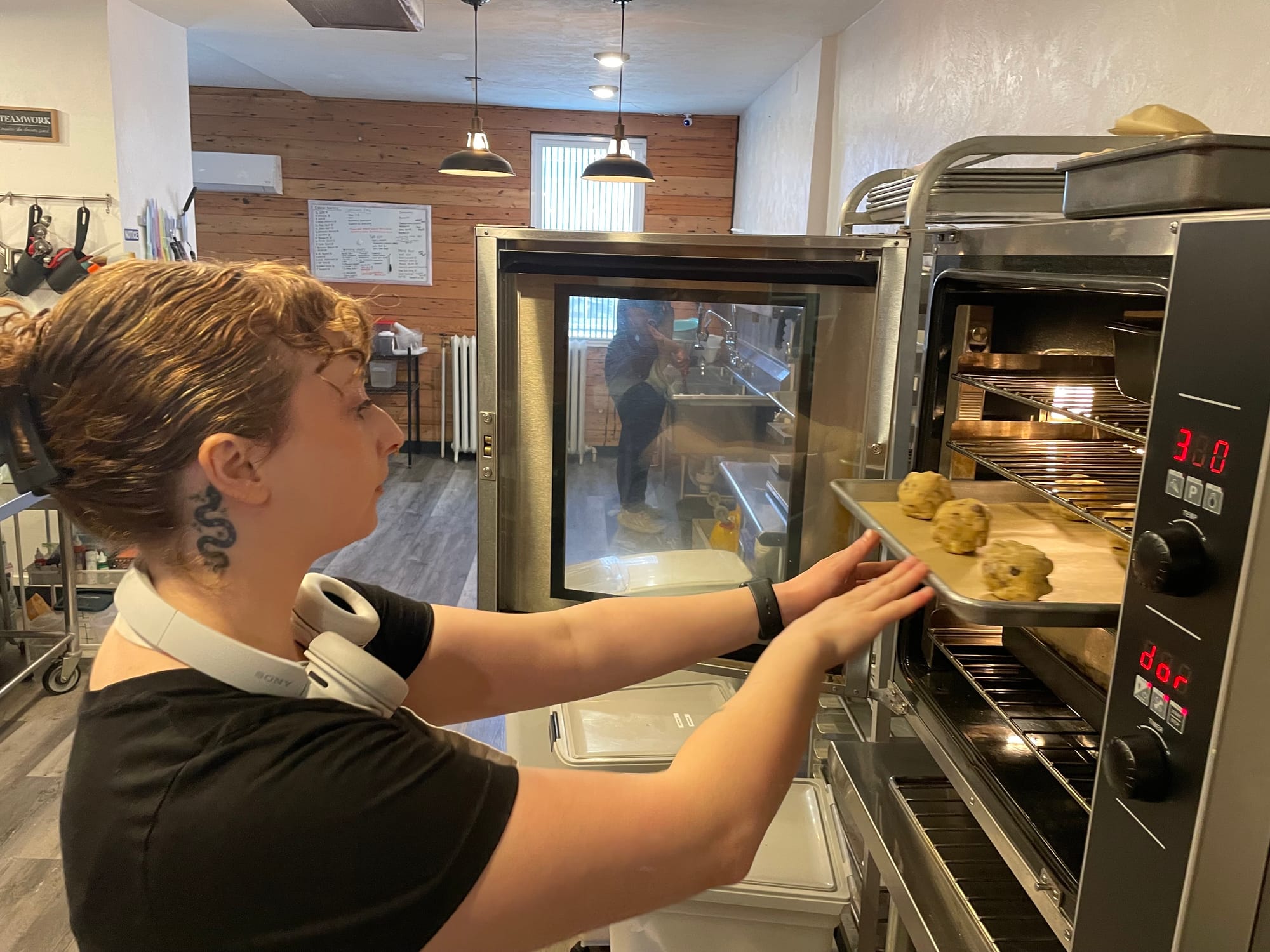 Veronica Rigatti puts a sheet of chocolate chip cookies in the oven at Mia & Maddie's Bakery.