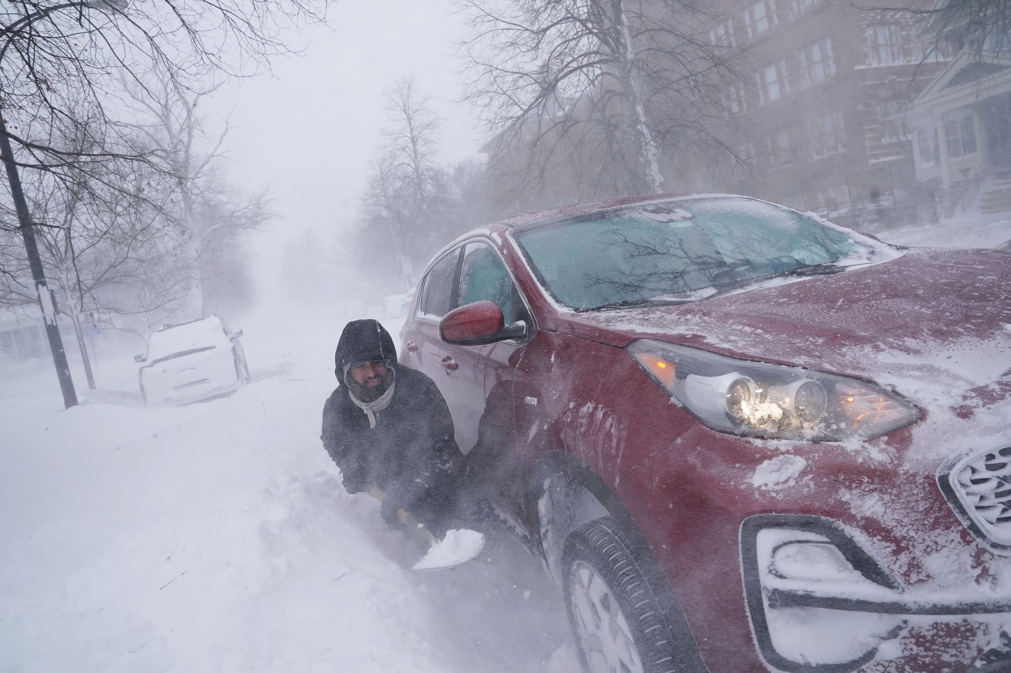 Gamaliel Vega tries to dig out his car on Lafayette Avenue after he got stuck in a snowdrift about a block from home while tr
