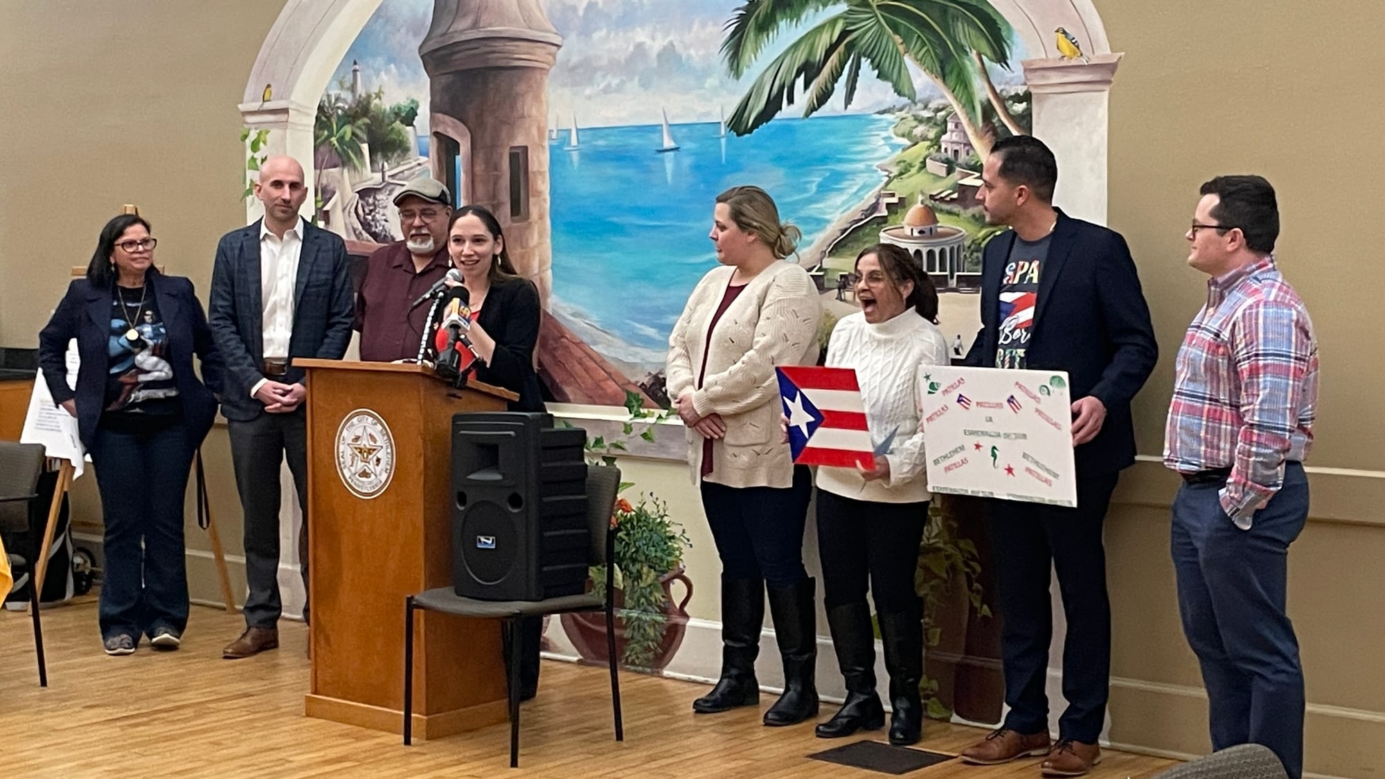 Janine Carambot Santoro, city director of equity and inclusion, opens the event at the podium.