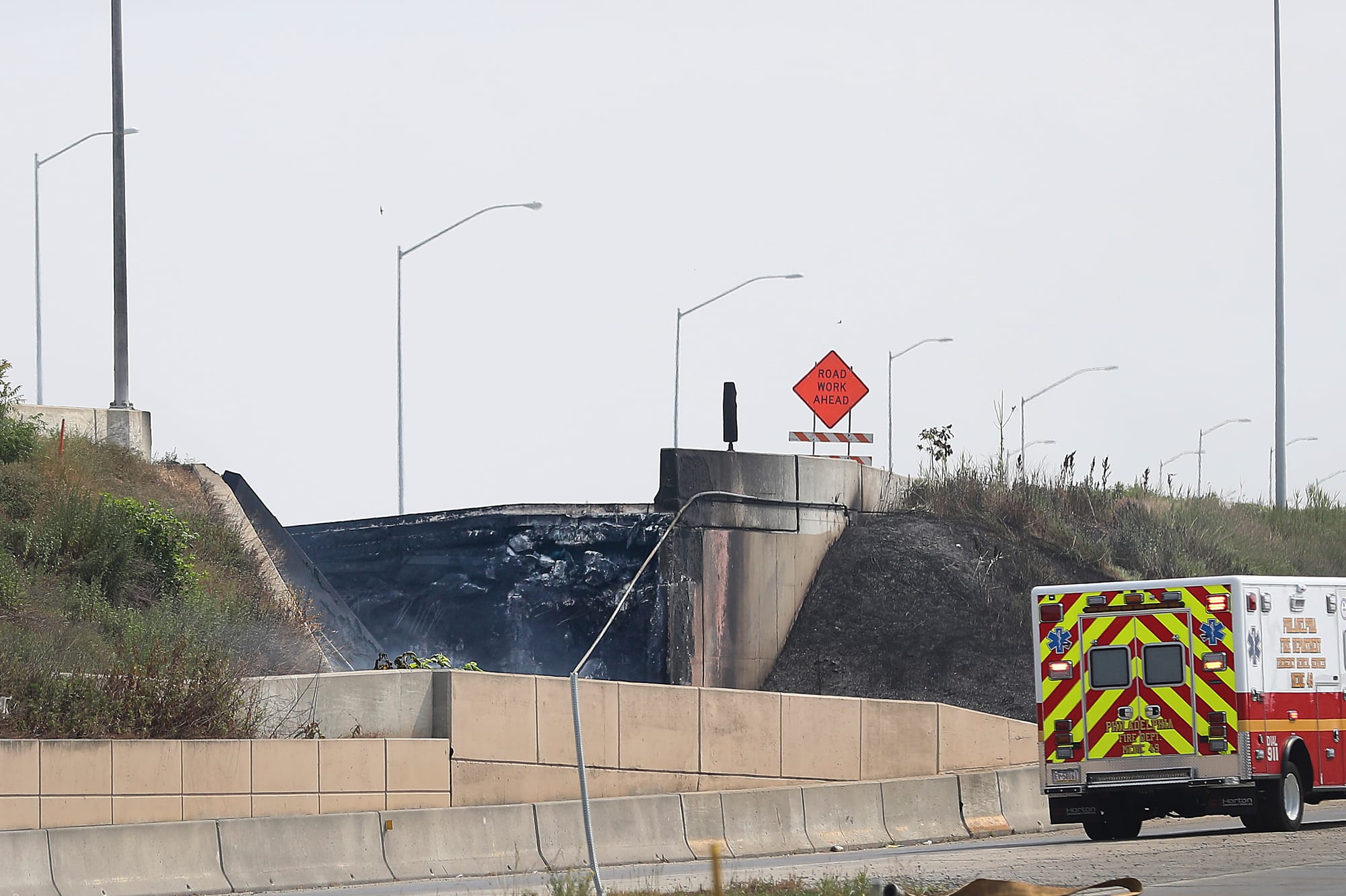Officials work at the scene following the collapse of an elevated section of Interstate 95 after a tanker truck caught fire, 