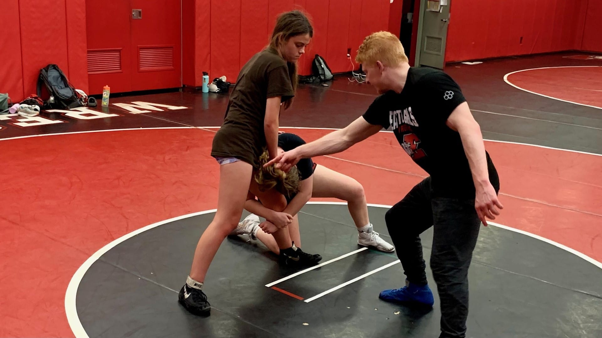 Easton Area junior varsity Coach Ryan Pomrinca teaches students Kendall Meixsell and Ruby Fairchild wrestling techniques