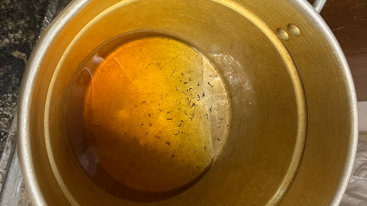 Yellow beeswax melts in the top of a double boiler.