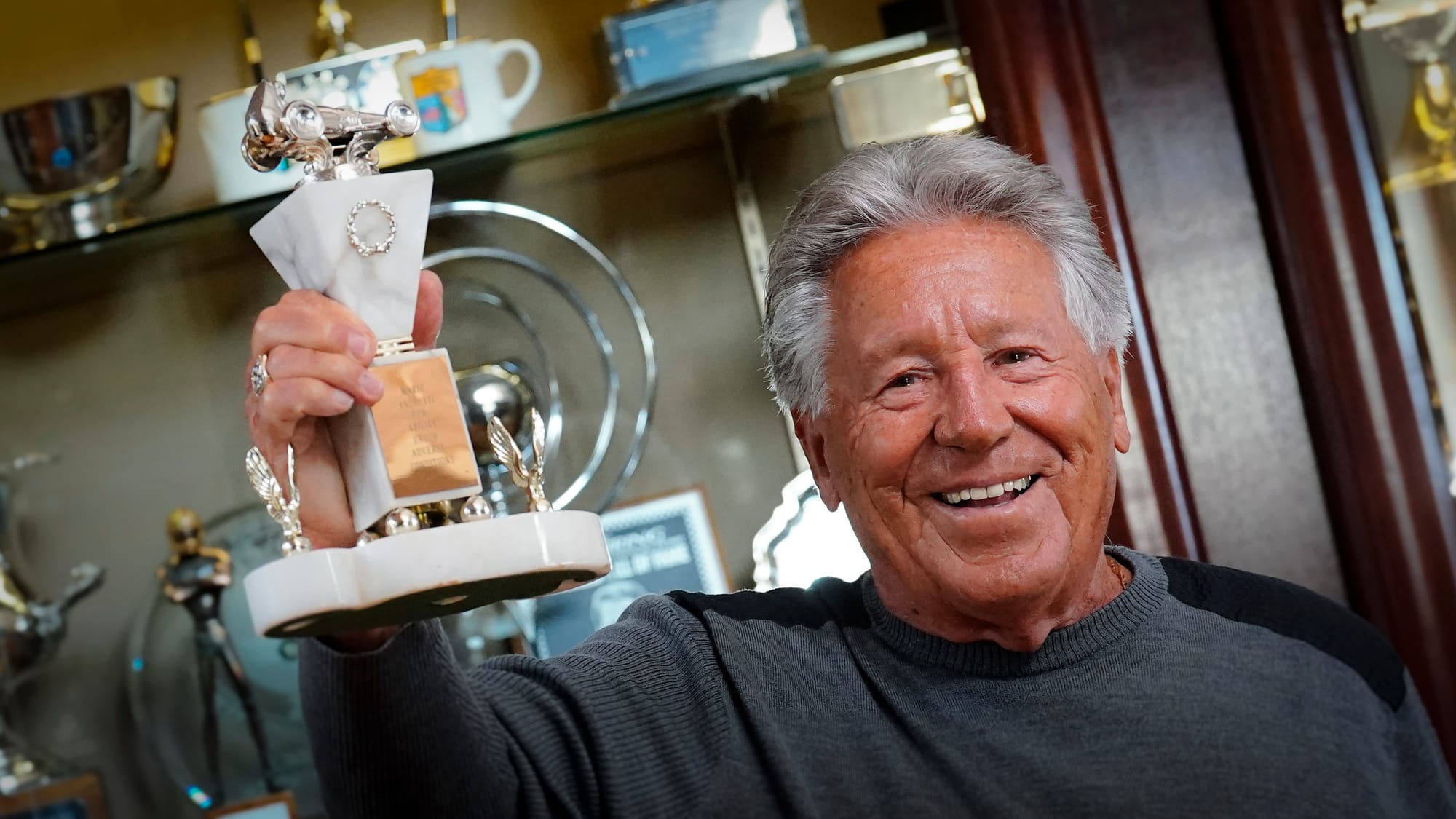 Race driver Mario Andretti shows the very first trophy he received. It was given at banquet in 1962 from a race when he "drov