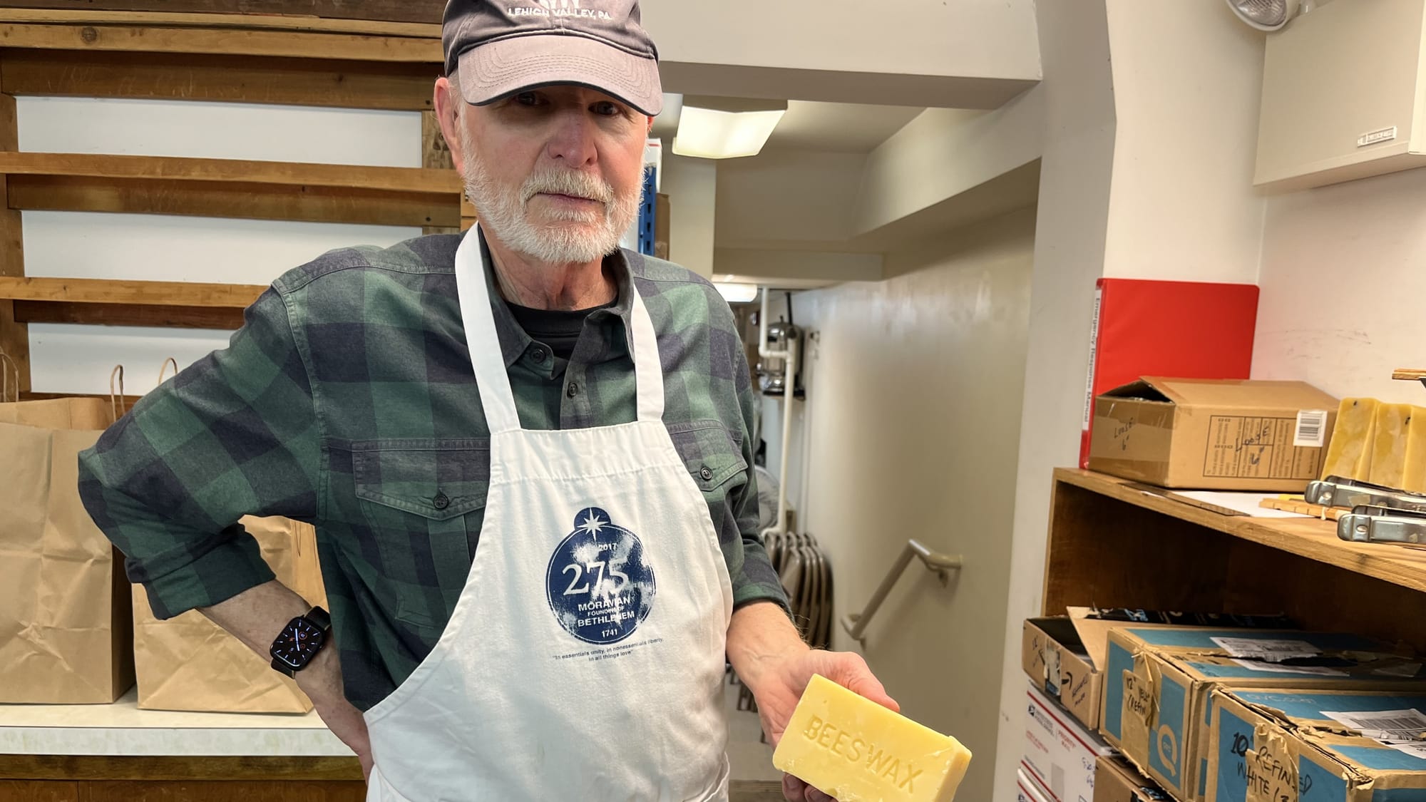 Harry Tachovsky holds a 1-lb. brick of yellow beeswax in the basement candle-making space at Central Moravian Church business