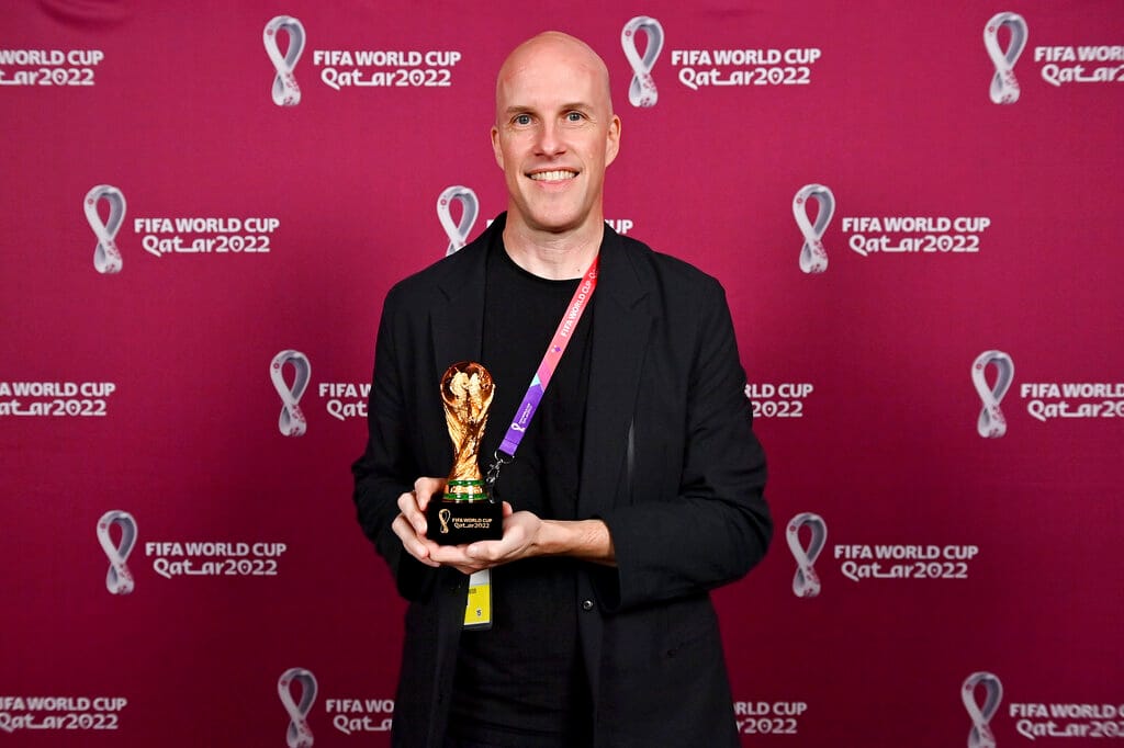 Grant Wahl smiles as he holds a World Cup replica trophy during an award ceremony in Doha, Qatar on Nov. 29, 2022. Wahl, one 