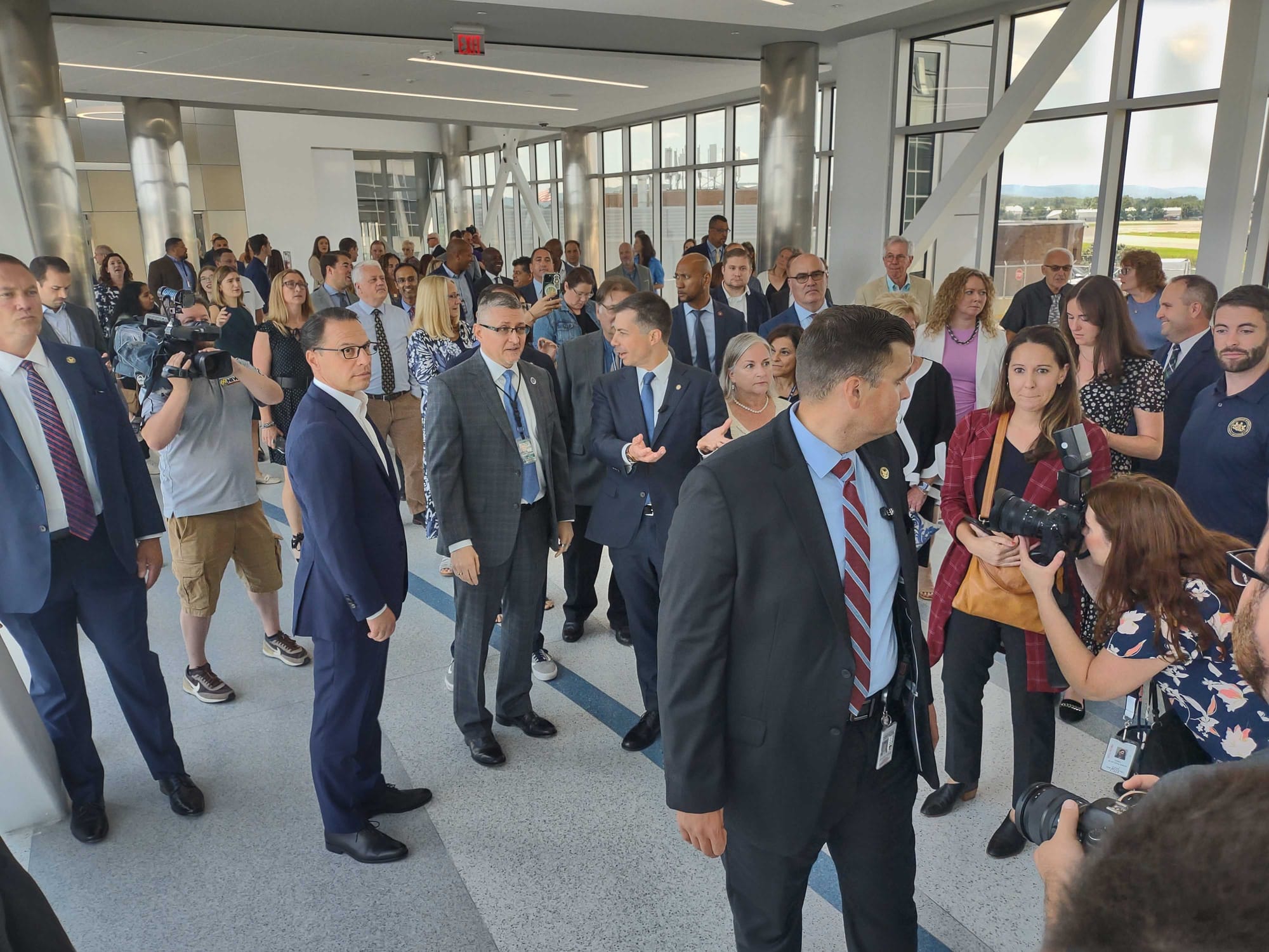 Secret Service agents create a perimeter around U.S. Transportation Secretary Pete Buttigieg as he speaks with Gov. Josh Shap