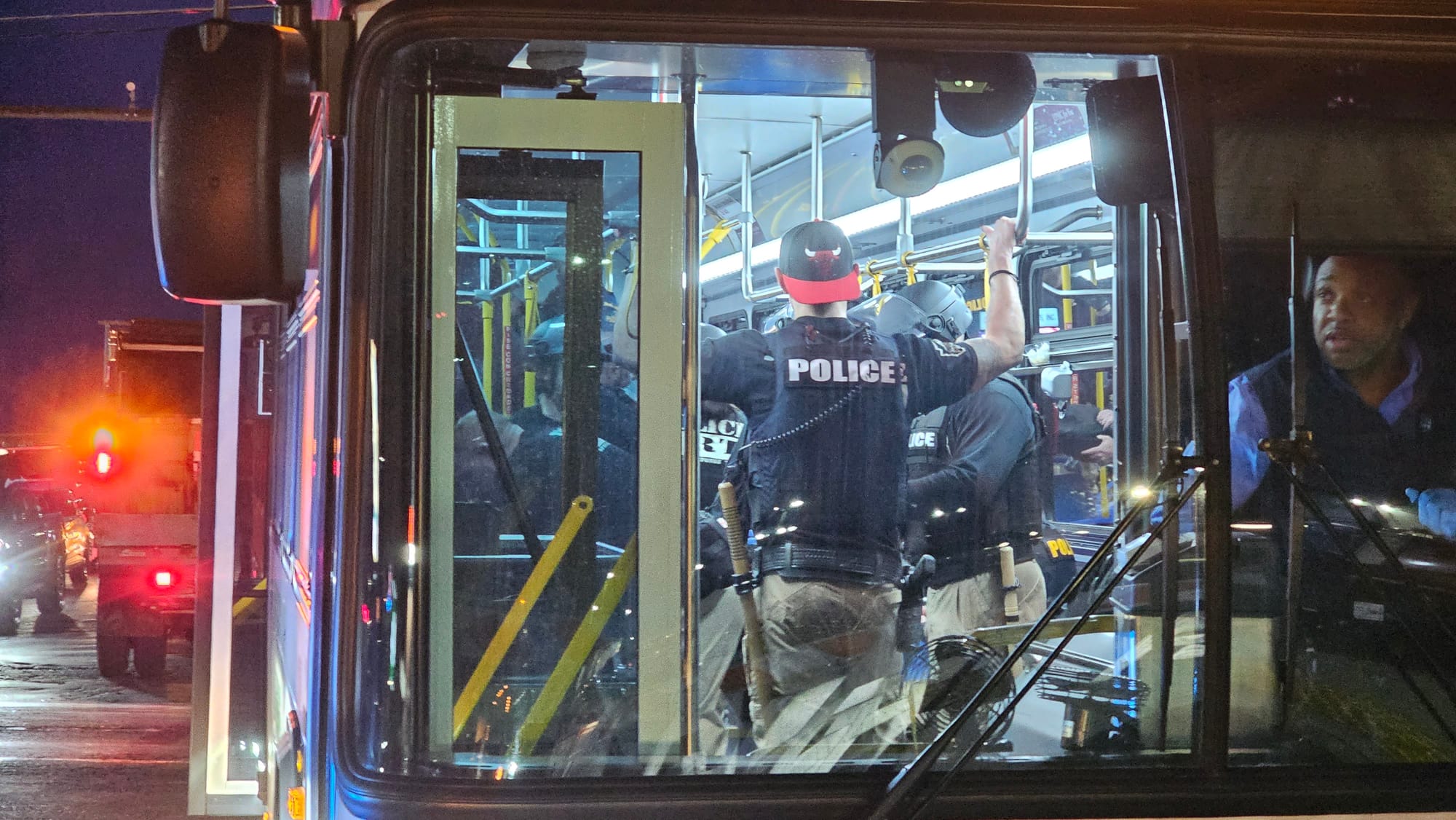 Allentown police officers equipped with batons and helmets board a LANTA bus after shielding President Joe Biden's motorcade 