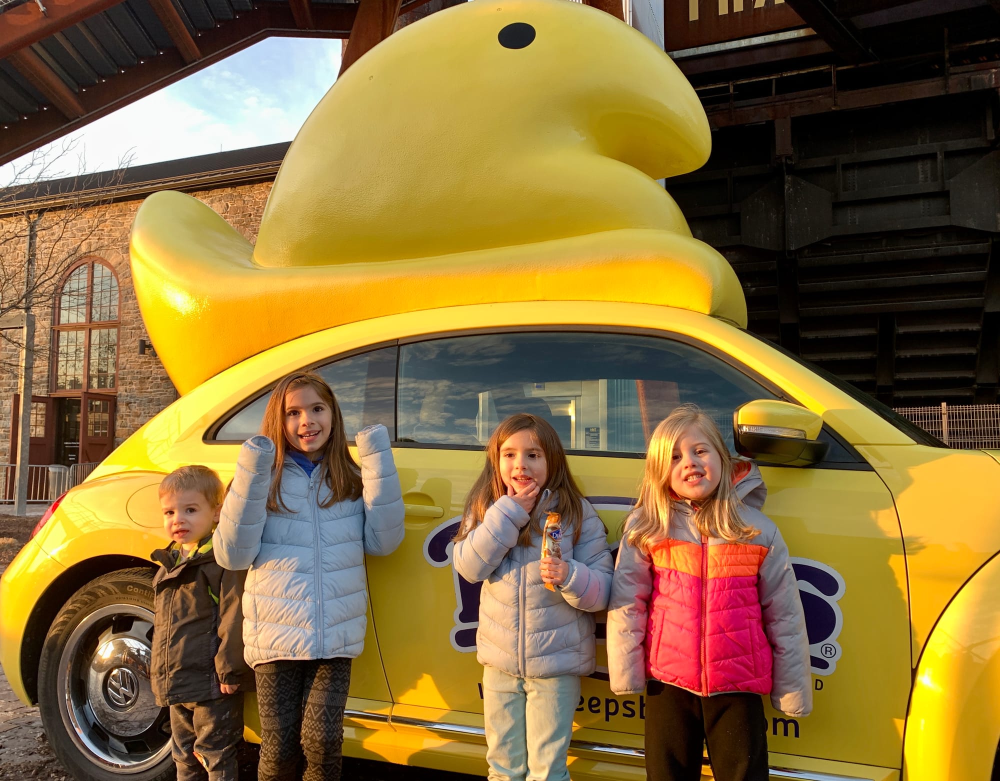 Kids stand in front of the Peeps car.