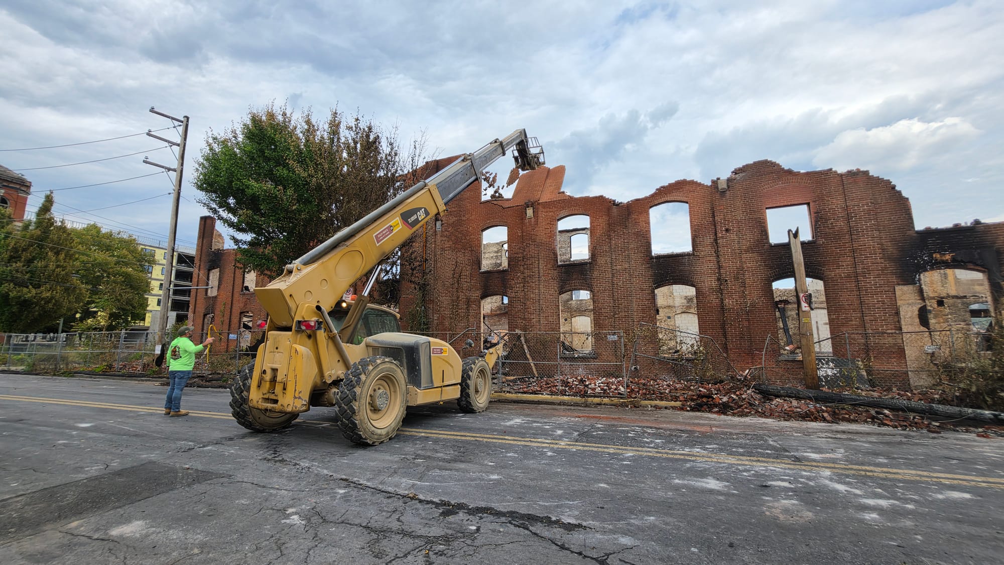 Crews knock down a portion of the outer wall of the former American Atelier furniture factory Thursday, June 25, after a blaz