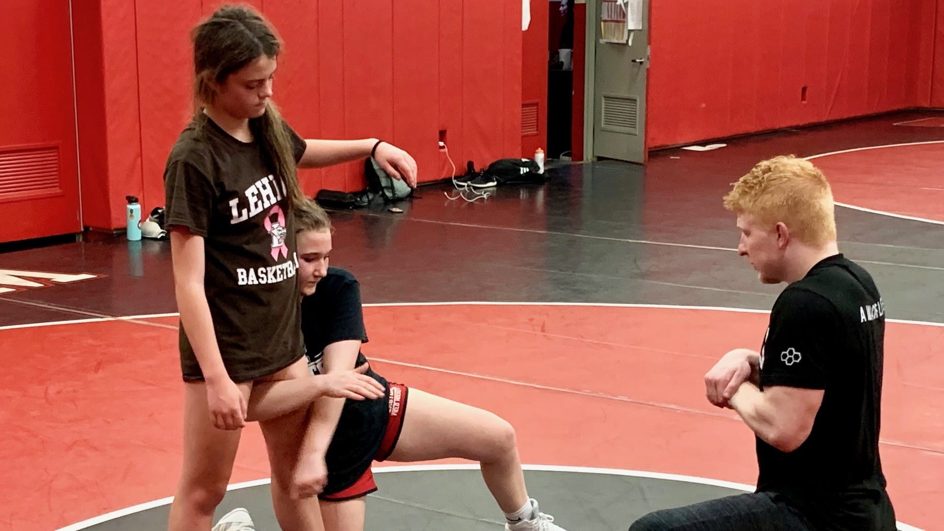 Easton Area junior varsity Coach Ryan Pomrinca teaches students Ruby Fairchild and Kendall Meixsell wrestling techniques