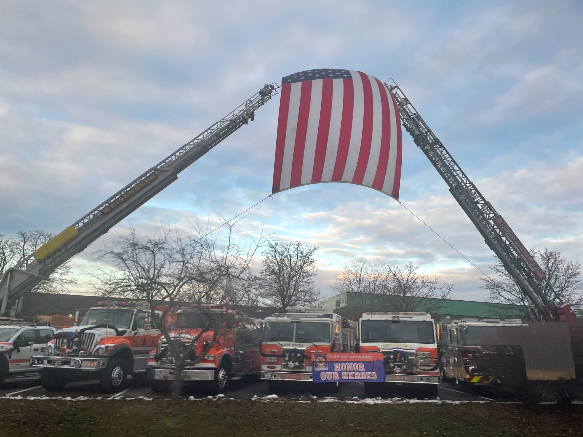 A flag flies high above fire trucks outside the funeral services for fallen New Tripoli firefighters