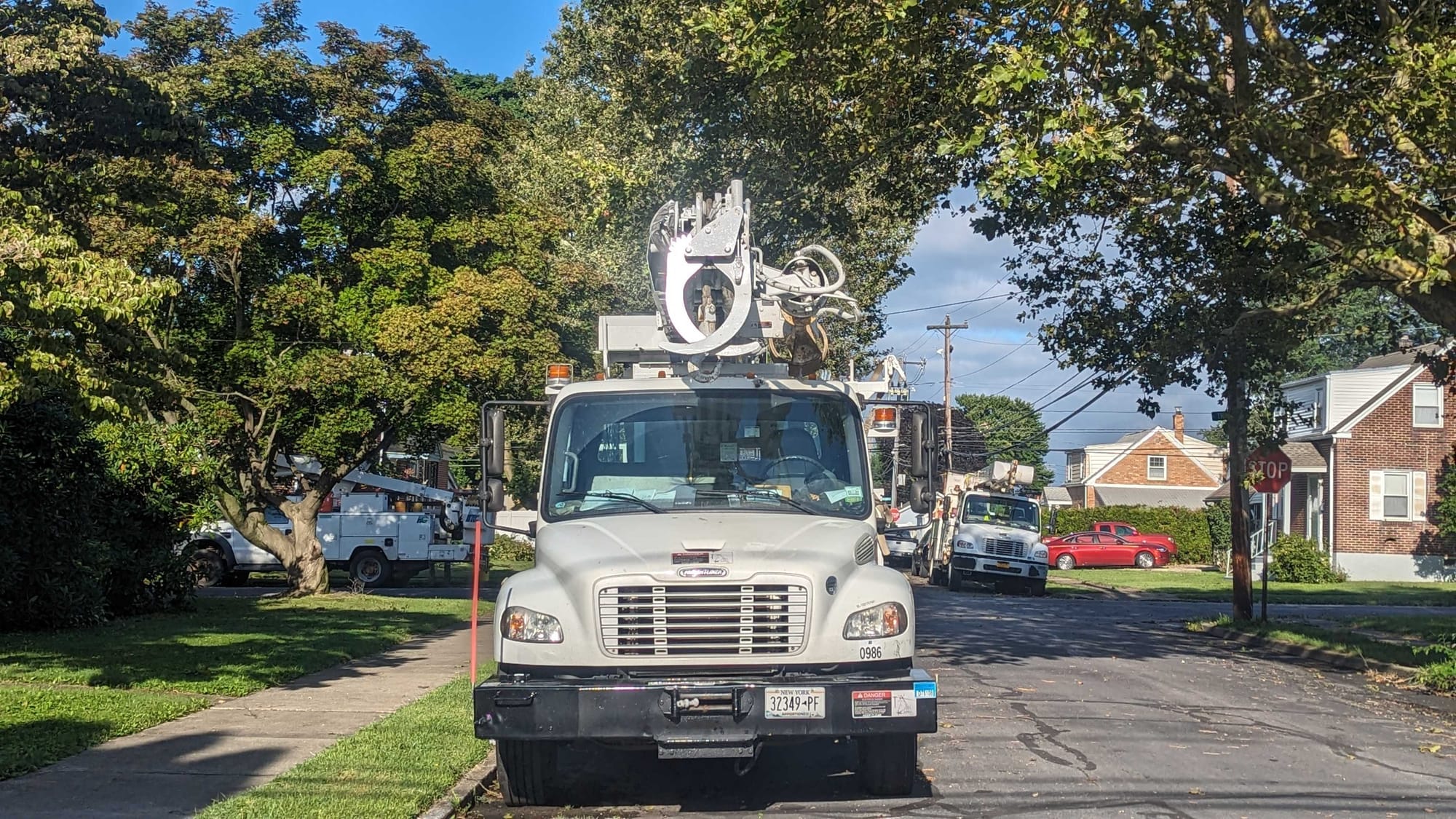 Three power trucks are staged on the street.