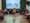 Dog mom and pup rock yellow poncho and gold-white vest. In the background in cursive font a large "Lara Bly" sign is nestled by a wall of green foliage. Attendees sit in a semi-cir...